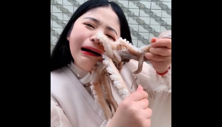 mujer intenta comer un pulpo y este se pega a su cara